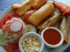 a white plate topped with meat and veggies next to dipping sauce on top of rice