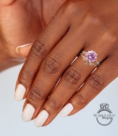 a woman's hand with white nails and a pink flower ring