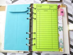 an open planner book sitting on top of a desk next to a binder and clipboard