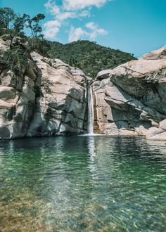 the water is crystal green and there are some rocks in front of it that look like they have waterfalls coming out of them