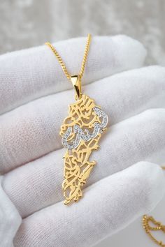 "Calligraphy poem verse: \" Lebanon, my beloved homeland, my heart cherishes you deeply.\" in arabic: بحبك يا لبنان يا وطني بحبك The necklace is made with genuine Moissanite stones (it will pass the diamond tester)  The word Lebanon is embezzled in stones Contains 0.26 CT of VVS1 Moissanite stones  This necklace is Handmade locally in our workshop in Toronto The base metal is 925 sterling silver Gold variant is bonded 3.0 microns of  pure 18K Gold. (considered as a vermeil jewellery) For solid gold options, please contact. CIPO. CERTIFICATE OF REGISTRATION 1199673 REGISTERED COPYRIGHT AND TRADE DRESS" Arab Necklace, Arabic Gold Necklace, Lebanon Necklace, Calligraphy Poem, Arabic Letter Necklace, Iraq Necklace, Lebanon Map, Arabic Necklace, Diamond Tester