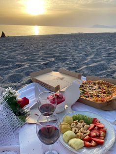 a pizza and fruit platter on the beach at sunset