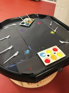 an art table with paint and brushes on it in the middle of a red floor