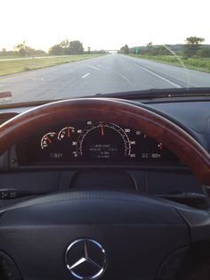 the dashboard of a car on a highway with grass and trees in the back ground