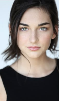 a close up of a person wearing a black shirt and blue eyes with long hair