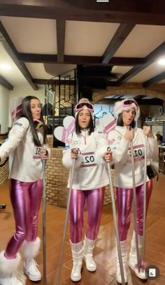 three women in pink and white outfits holding ski poles