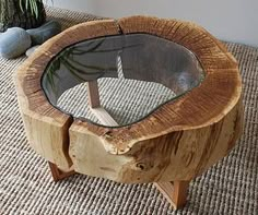 a wooden table with glass top sitting on a rug next to a potted plant