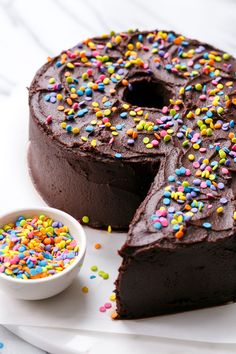 a chocolate cake with sprinkles and a slice cut out on the side