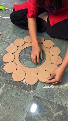 a woman sitting on the floor making a circle out of cardboard circles with her hands