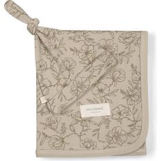 a blanket with flowers on it and a tag hanging from the front, in beige