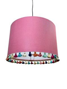 a pink lampshade with tassels hanging from the ceiling and a white background