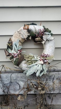 a wreath is sitting on the side of a house next to some plants and twigs