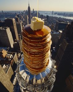 a stack of pancakes with butter on top of it in the middle of a city