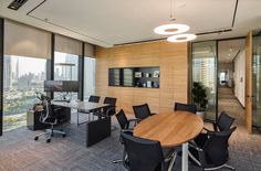 an empty conference room with black chairs and wooden table in front of large windows overlooking the city