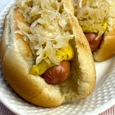 two hotdogs with sauerkraut and mustard on a plate