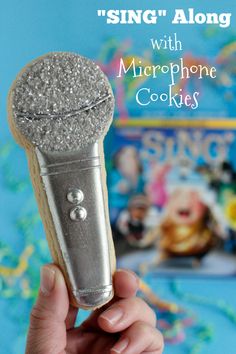 someone is holding up a cookie shaped like a microphone with the words sing along on it