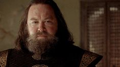 a bearded man with long hair and beard wearing armor