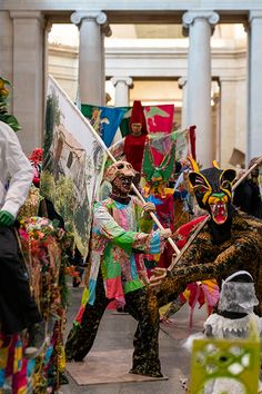 some people are dressed up in costumes and holding flags while walking through a building with columns