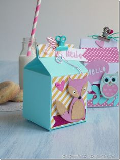 two small boxes with tags on them sitting next to doughnuts and milk bottles