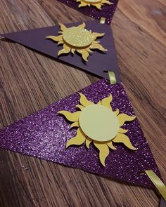 three purple and gold paper sun decorations on a wooden table