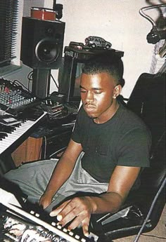 a young man sitting in front of a mixing desk with electronic equipment on top of it