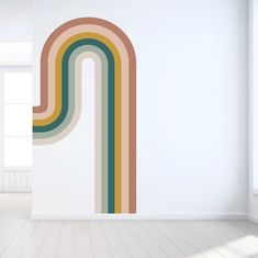 an empty room with white walls and a large rainbow wall sticker on the wall