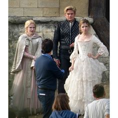 the actors are dressed in period costumes and talking to each other while others look on