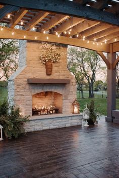 an outdoor fireplace with string lights and potted plants