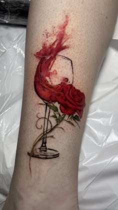 a woman's leg with a rose and wine glass tattoo on her left calf