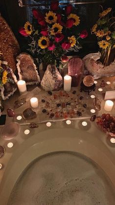 candles are lit in the middle of a bathtub with rocks and flowers on it