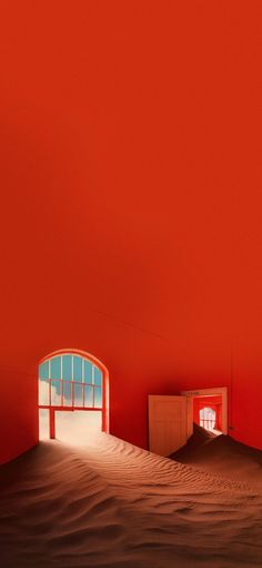 an empty room with red walls and sand dunes in the foreground, there is a small window on the far wall