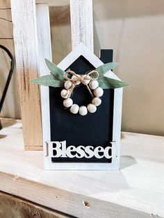 a wooden frame with a wreath on it and the word blessed written in white letters