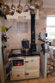 an old fashioned stove with pots and pans hanging from the ceiling