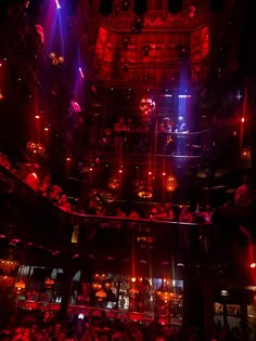 a large group of people in a dark room with red and blue lights on the ceiling