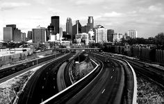 a black and white photo of a city skyline with train tracks in the foreground