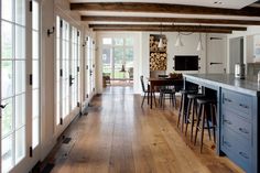 a large kitchen with wooden floors and white walls, along with an island in the middle