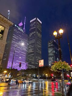 a city street at night with tall buildings in the background