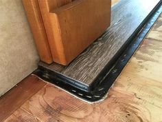 a wood floor with a wooden door on the side and a black strip under it