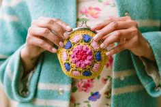 a woman is holding a small purse with crocheted flowers on the front and sides