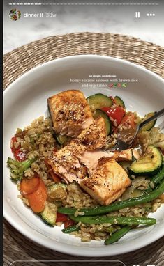 a white plate topped with meat and veggies on top of rice next to a fork