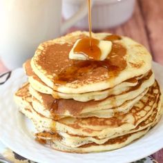 a stack of pancakes with syrup being poured on top