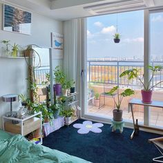 a bedroom with large windows and plants in the corner