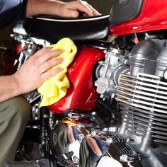 a man polishing a red motorcycle with a yellow microfil cloth on it