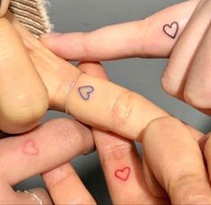 three fingers with hearts tattooed on them