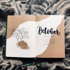 an open notebook with the word october written in black ink on it and a tree