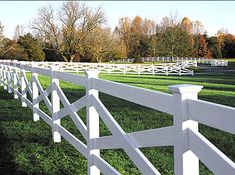 a white fence in the middle of a grassy field