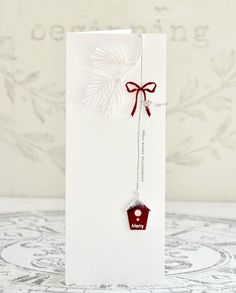 a white card with a red bow on it and a tag hanging from the front