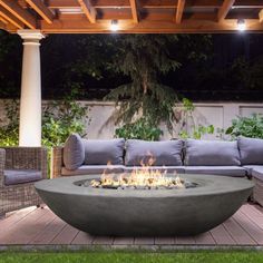 an outdoor fire pit sitting on top of a wooden deck next to a couch and table