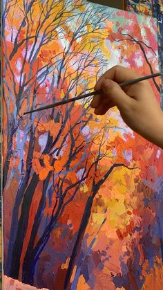 someone is painting an autumn scene with trees and oranges on the canvas, while holding a brush in their left hand