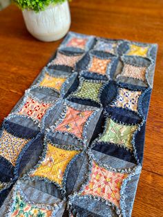 a table runner made out of old jeans with colorful patchwork on the edges and sides